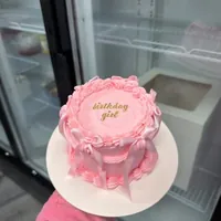 A pink mini cake piped with birthday girl, with pink ruffles and bows