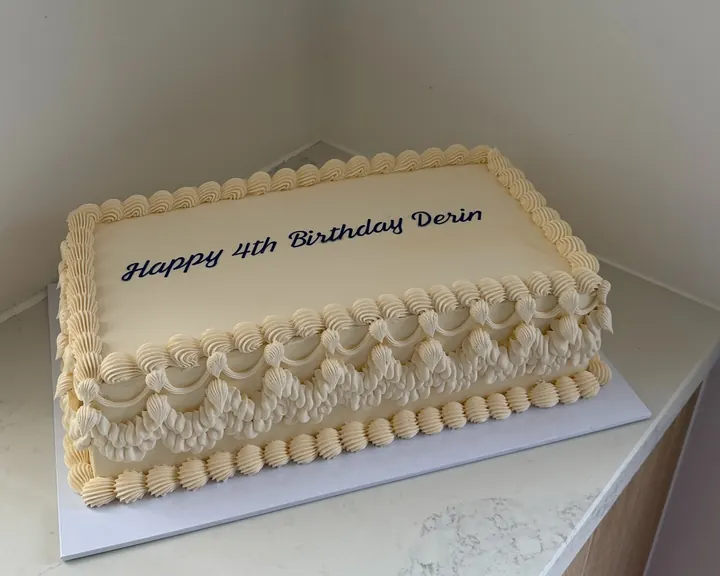 Rectangle cake in cream buttercream with vintage shell and swag piping, written Happy 4th Birthday Derin