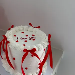 White cake with red ribbon bows, little red hearts and I love you on top