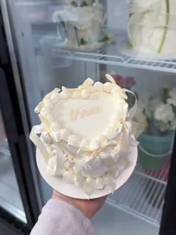 Ivory heart mini cake with a gold script name and ivory bows