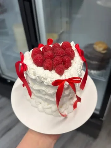White heart mini cake topped with raspberries and red bows
